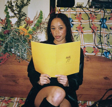 Woman sitting holding a yellow Juliet Johnstone branded menu